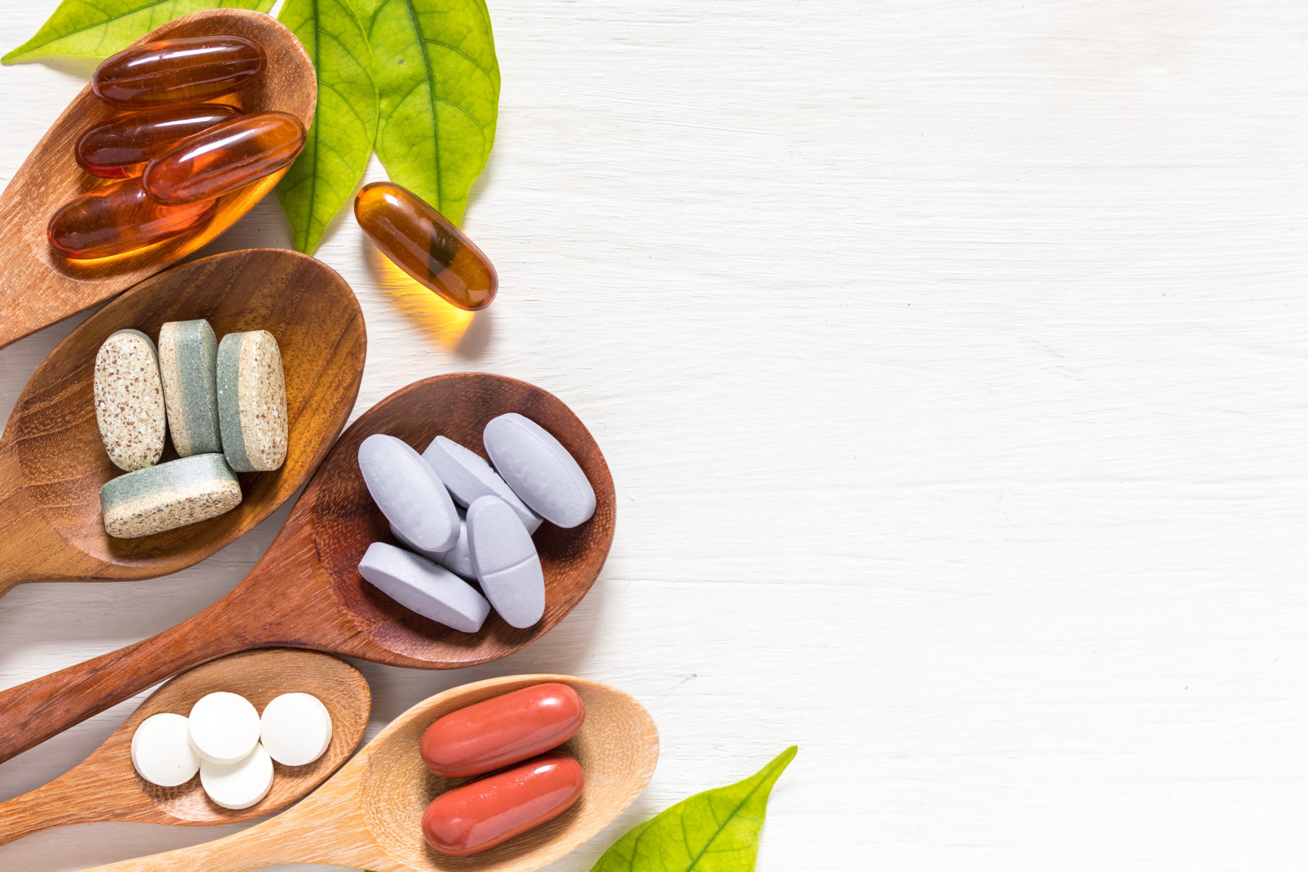 Multivitamins on spoons with leaves