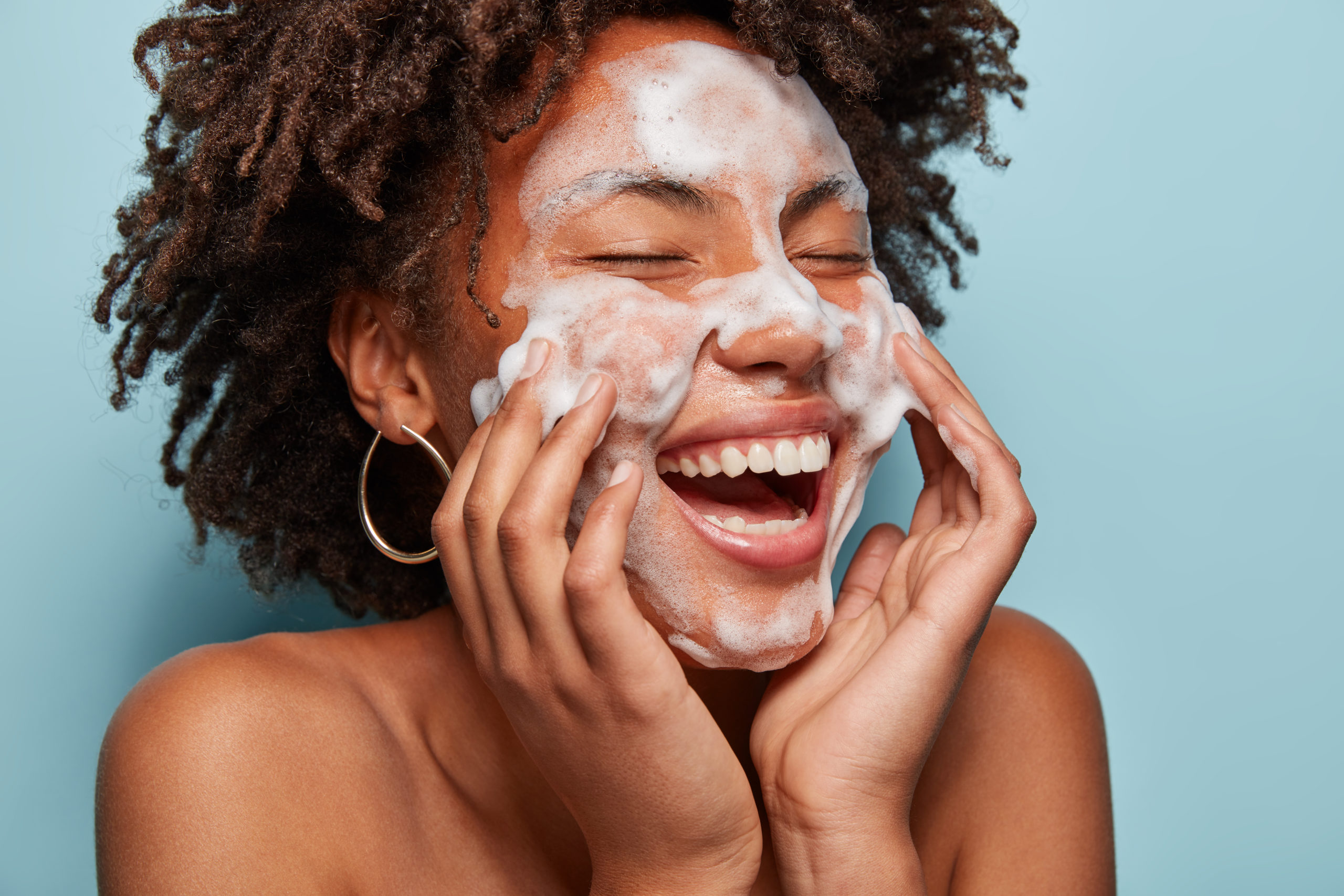 Cheerful woman washing her face and smiling